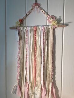 a pink and white wall hanging with ribbons