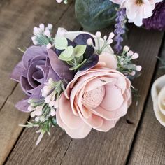 a bouquet of flowers sitting on top of a wooden table next to another flower arrangement