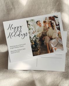 an envelope with the words happy holidays written on it and two photos of people sitting next to each other