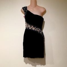 a black dress with beading on the shoulders and one shoulder is displayed in front of a mannequin