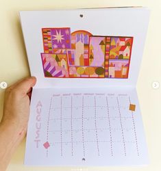 a person holding up a calendar with the word happy written on it in bright colors