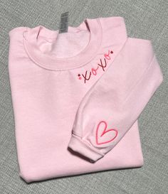 Embrace the language of love with our cozy and chic XOXO embroidered sweatshirt! Crafted with care, this soft pink crewneck sweater is a perfect blend of comfort and style. Adorned with a charming XOXO embroidery in a contrasting thread, this sweatshirt is an instant mood booster and a staple for your casual wardrobe. The delicate heart detailing on the sleeve adds a touch of whimsy and keeps love close to your heart. Ideal for lounging at home, casual outings with friends, or as a sweet gift fo Pink Crew Neck Sweater With Ribbed Cuffs, Cute Pink Sweatshirt With Ribbed Cuffs, Trendy Embroidered Pink Sweatshirt, Pink Long Sleeve Top With Letter Embroidery, Cute Crew Neck Sweatshirt With Ribbed Cuffs, Pink Long Sleeve Sweatshirt With Embroidered Text, Pink Letter Embroidery Top For Winter, Pink Winter Tops With Letter Embroidery, Trendy Pink Embroidered Sweater