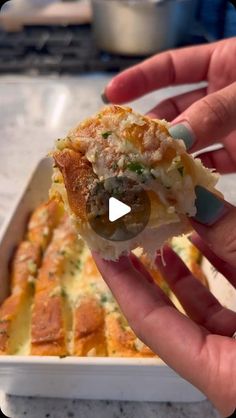 a hand holding a piece of food in front of a casserole dish