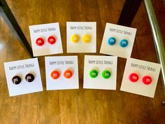 five different colored buttons on white cards sitting on a wooden floor next to a chair