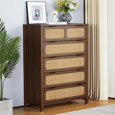 a brown dresser sitting next to a potted plant on top of a hard wood floor