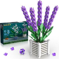 purple flowers are in a white vase next to a box