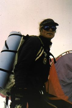 a man holding a surfboard next to a tent