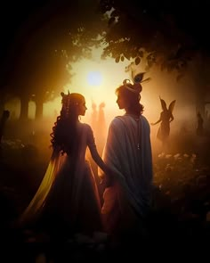 two people dressed in white standing next to each other on a forest floor at sunset