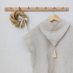 a sweater hanging on a coat rack next to a wooden hanger with a scarf