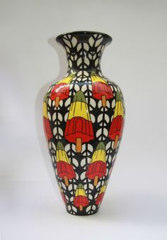 a colorful vase with red, yellow and green designs on the bottom is sitting against a white background