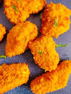 several pieces of fried food sitting on top of a blue plate with green sprigs