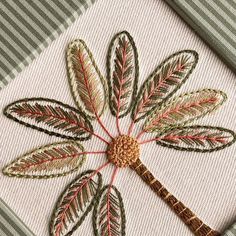 a close up of a cross stitch on a piece of cloth with a dragonfly