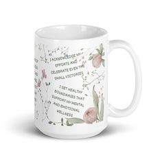 a white coffee mug with pink flowers and words on the side, in front of a white background