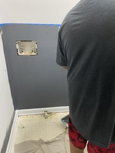 a man is standing in the corner of a bathroom