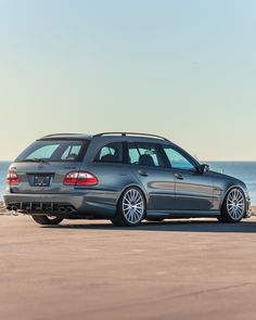 a silver car parked on the beach next to the ocean