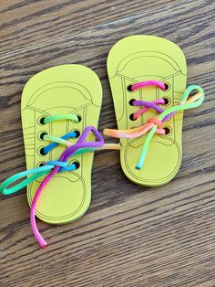 a pair of yellow sandals with colorful laces tied to them on top of a wooden table