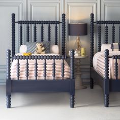 two twin sized beds with blue headboards and foot boards, one has a teddy bear on the bed