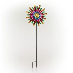 a multicolored pinwheel on a black metal pole with a white back ground