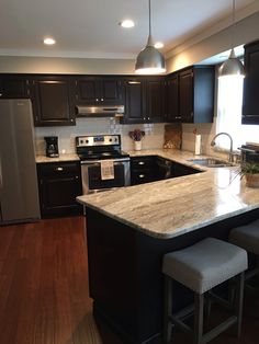 a kitchen with black cabinets and an island in the middle is lit by two pendant lights