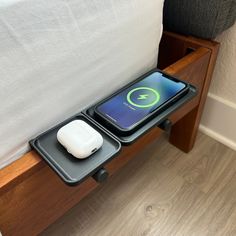 two cell phones sitting on top of a wooden table next to a charging station with an external charger