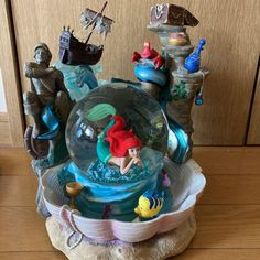 the little mermaid figurine is sitting on top of a bowl with other toys