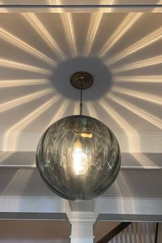 a light fixture hanging from the ceiling in a room with white walls and wood beams