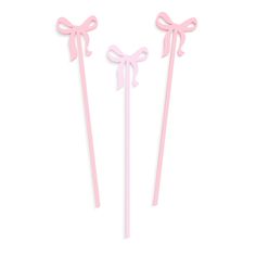 two pink bow - tied cake picks on a white background, one has a ribbon and the other has a bow