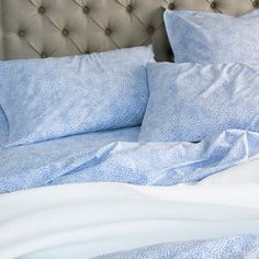 a bed with blue sheets and pillows on it