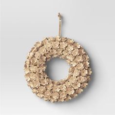 a wreath made out of flowers hanging from a hook on a gray wall in front of a white background