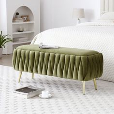 a green bench sitting on top of a white rug next to a bed and nightstand