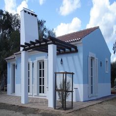 a blue house with white shutters on the front and side windows, next to a cactus