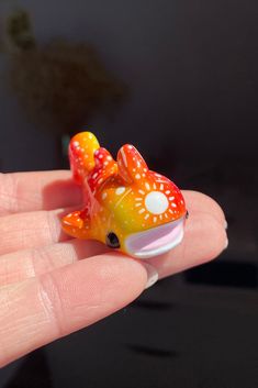 a small toy fish sitting on top of someone's finger