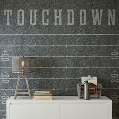 a white dresser sitting in front of a wall with writing on it and a lamp next to it