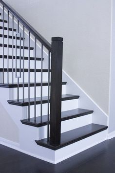 there is a black and white stair case next to the bannister in this house