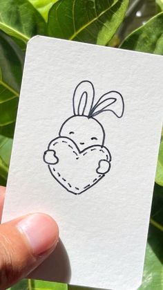 a hand holding up a small card with a drawing of a rabbit on it's face