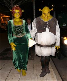 two people in costumes standing next to each other on a sidewalk at night with one person dressed as shrat and the other wearing a costume