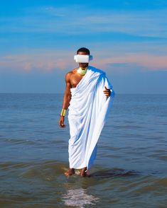 a man standing in the water with a towel wrapped around his head and blindfold