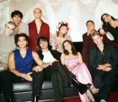 a group of people sitting on top of a couch in front of a white wall