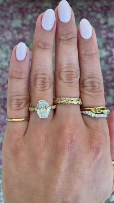 a woman's hand with three different rings on her fingers and one ring in the middle