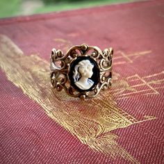 Victorian style antiqued brass filigree ring which is fully adjustable.At its center is a 10x8mm black and white womans profile cameo.   Other cameo color options are available as well.Also available in antiqued silver. Womans Profile, Gold Marquise Ring, Silver Celtic Rings, Opal Solitaire Ring, Turquoise Statement Ring, White Lady, Purple Lady, Wholesale Jewelry Supplies, Turquoise Gold Ring