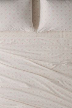 an unmade bed with white sheets and pink flowered comforter on the bottom