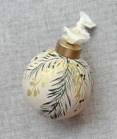 a white ornament with green and yellow leaves on it sitting on a gray surface