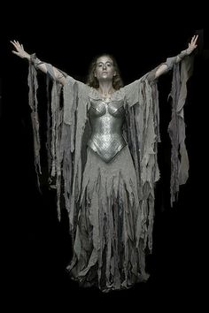 a woman dressed in silver and holding her arms out