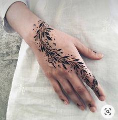 a woman's hand with a black and white tattoo design on the left palm