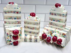 three pieces of cake with white frosting and sprinkles on them, one slice has cherries