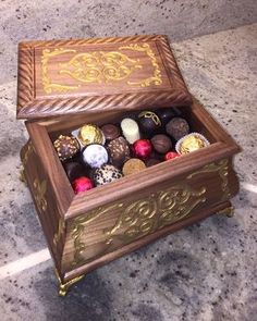 a wooden box filled with assorted chocolates sitting on top of a marble floor