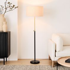 a living room with a white couch and a black floor lamp in the corner next to a coffee table