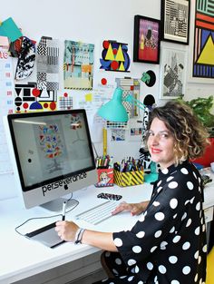 a woman sitting at a desk in front of a computer monitor with a keyboard and mouse