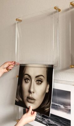 a woman is holding up a photo hanging from the wall