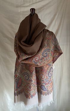 Very Finely woven Cocoa with off white and  multicolor border Kani paisley wool shawl, handwoven in Kashmir, India. This beautiful shawl has a slightly sheer cocoa color interior with a floral jacquard design and a wonderful multicolor paisley border. I show this shawl folded in half lengthwise on the mannequin to show a option to work with the wide width of this shawl. The back of the paisley area has been hand-cut to take away the "floats" to lighten the weight of the border.  This technique is called Kani and is considered a more valuable weaving technique than jamavar weaving.  Jamavar is reversible but not as densely woven as the Kani.  Most of these Paisley shawls are woven as  limited edition groups. This is the last few of a group of 10.  They are collector's items and are a beauti Paisley Border, Kashmir India, Paisley Shawl, Color Interior, Jacquard Design, Fine Craft, Wool Shawl, Floral Jacquard, Craft Work